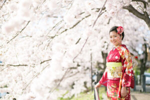 桜の前に立つ振袖姿の女性