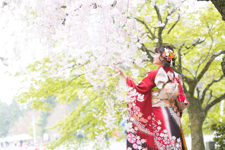 葉桜に囲まれた振袖姿の女性